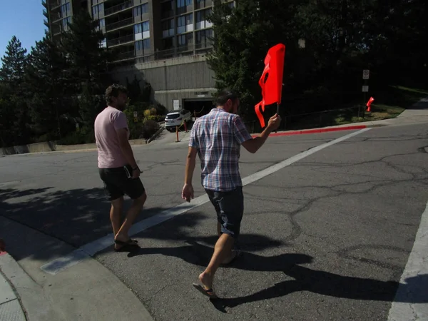 Salt Lake City, ABD - 08 18 2017: İki pedastian yüksek görüş mesafesi olan turuncu bir bayrak ile karşıdan karşıya geçiyor