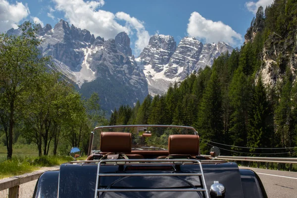 Arka planda İtalyan dolomitleri olan klasik bir araba. Klasik araba bir yaz tatili sırasında bir tur yapıyordu. Turizm için stil ve yolculuk kavramı