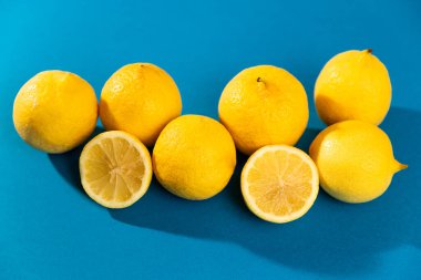 Altı sarı limon (meyve) ve iki yarım meyve grubu. mavi arka plan. Stüdyo fotoğrafı.