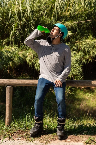 Rollschuhfahrer Mit Zyanhelm Und Trinkt Wasser Aus Einer Grünen Flasche — Stockfoto