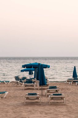 Benidorm plajı boş, insan yok. Hamaklar, şemsiyeler, bulutlu bir gün. Salgın, koronavirüs