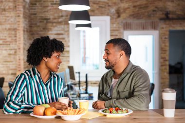 İki meslektaş ofiste sağlıklı bir mola veriyor. Sohbet ederken taze meyve, atıştırmalık ve içeceklerin tadını çıkarıyorlar.
