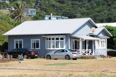 Auckland / Yeni Zelanda - 31 Ocak 2020: Önünde arabalar olan Piha sahilindeki yazlık ev manzarası