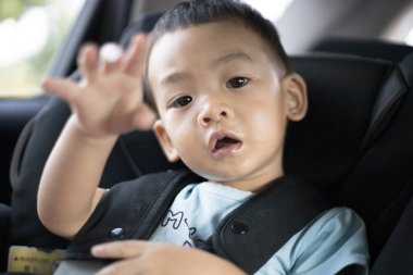 1 yaşındaki sevimli Asyalı çocuk araba portresindeki koltuktan etrafına bakıyor. Aile Gezileri ve Bebek Bakımı ve Güvenlik Konsepti. Ön Görünüm Vesikalık Yakın Çekim Kopyalama Arkaplanı ve Bulanık Arkaplan.
