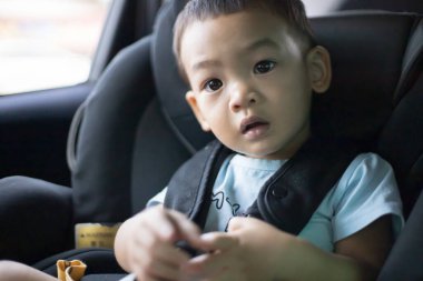 1 yaşındaki sevimli Asyalı çocuk araba portresindeki koltuktan etrafına bakıyor. Aile Gezileri ve Bebek Bakımı ve Güvenlik Konsepti. Ön Görünüm Vesikalık Yakın Çekim Kopyalama Arkaplanı ve Bulanık Arkaplan.