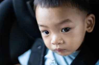 1 yaşındaki sevimli Asyalı çocuk araba portresindeki koltuktan etrafına bakıyor. Aile Gezileri ve Bebek Bakımı ve Güvenlik Konsepti. Ön Görünüm Vesikalık Yakın Çekim Kopyalama Arkaplanı ve Bulanık Arkaplan.