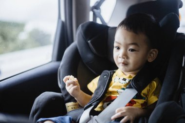 1 yaşındaki sevimli Asyalı çocuk araba portresindeki koltuktan etrafına bakıyor. Aile Gezileri ve Bebek Bakımı ve Güvenlik Konsepti. Ön Görünüm Vesikalık Yakın Çekim Kopyalama Arkaplanı ve Bulanık Arkaplan.