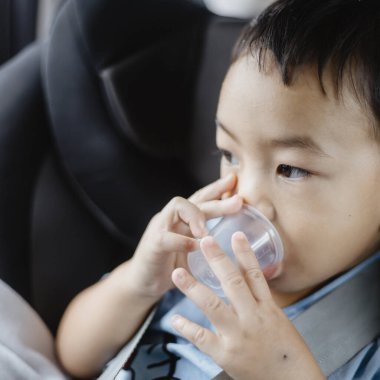 1 yaşındaki sevimli Asyalı çocuk araba portresindeki koltuktan etrafına bakıyor. Aile Gezileri ve Bebek Bakımı ve Güvenlik Konsepti. Ön Görünüm Vesikalık Yakın Çekim Kopyalama Arkaplanı ve Bulanık Arkaplan.