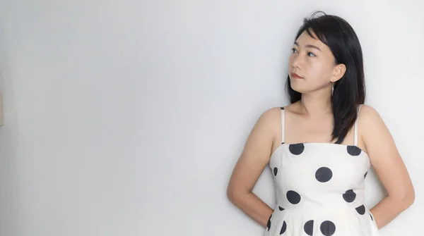 Portrait of beautiful adult (40 years old) Asian woman in polka dots dress with arms crossed and pretending straight face over isolated white background. People\'s body authentic and feeling concept.