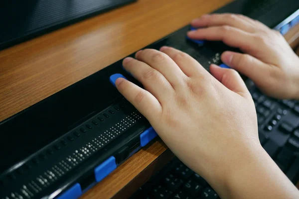 Close-up blind person hands using computer with braille display or braille terminal a technology assistive device for persons with visual disabilities.