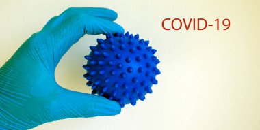 COVID-19 pandemik koronavirüs konsepti. Doktor elinde koronavirüsün soyut bir modelini tutuyor. Eldivenli el. Covid19 yazıtları.