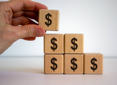 Erkek el piramidin tepesine dolar işareti olan bir küp yerleştiriyor. Güzel beyaz arkaplan.