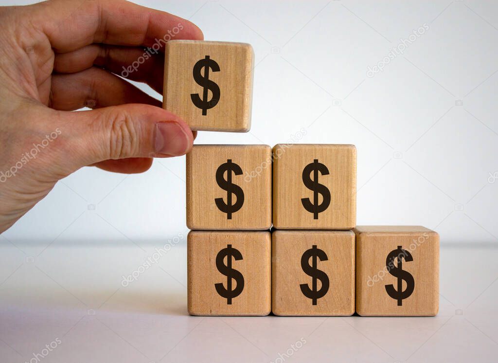 Male hand placing a cube with dollar sign on top of a pyramid. Beautiful white background.