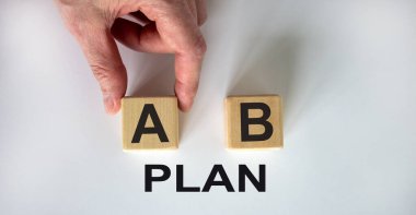 Erkek el, beyaz arka planda A ve B harfleri olan iki küp arasında seçim yapıyor. 'Plan' kelimesi.
