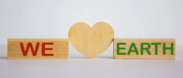 'We love earth' words concept on wooden blocks. White background. Wooden hearts.
