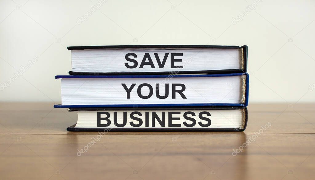 Books with text 'save your business' on beautiful wooden table. White background. Business concept.