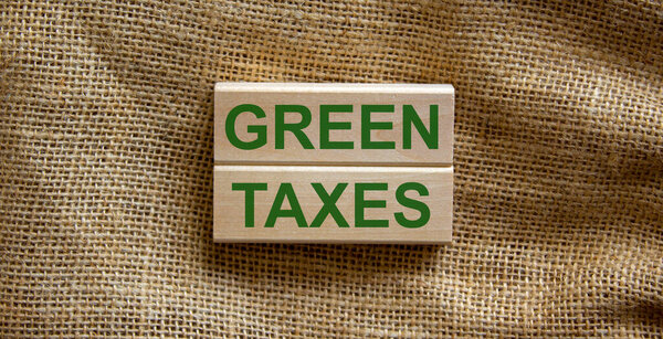 Wooden blocks form the text 'green taxes' on beautiful canvas background. Ecology concept.