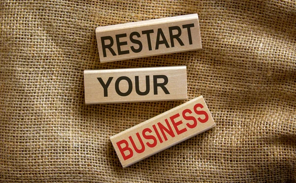 Wooden blocks form the text 'restart your business' on beautiful canvas background.