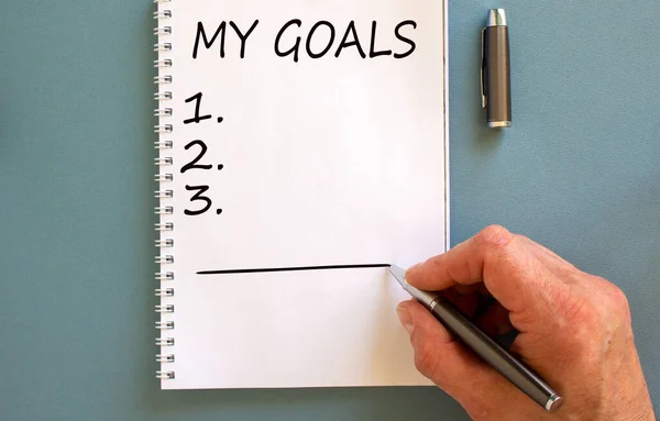 Male Hand Writing Goals White Note Isolated Blue Background — Stock Photo, Image