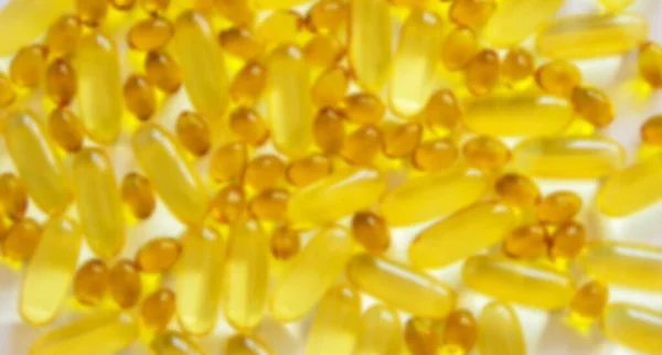 Yellow vitamins tablets, fish oil, Omega Vitamin E. Pills on a white background. Web banner. Beautiful background. Blurred image.