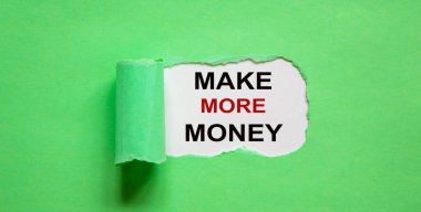 Yırtık yeşil kağıdın arkasında görünen 'daha çok para kazan' metni.