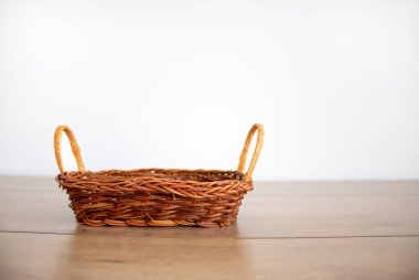 Güzel ahşap bir masada beyaz arka planda küçük boş bir hasır sepet. Boşluğu kopyala.