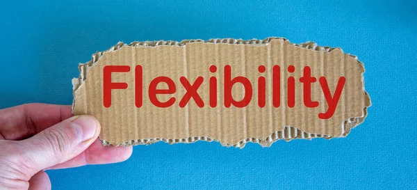 Word \'flexibility\' on the piece of cardboard between fingers.