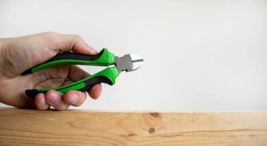 Bir erkek eli, tahta bir çubukta tel kesiciyi tutuyor. Güzel beyaz arka plan. Boşluğu kopyala.