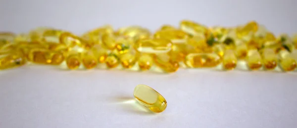Yellow vitamins tablets, fish oil, Omega Vitamin E. Pills on a white background. Web banner with a copy space.