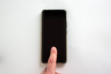 Adamın parmağı beyaz arka plandaki akıllı telefonun kilidini açıyor. Metnin için boşluk kopyala.