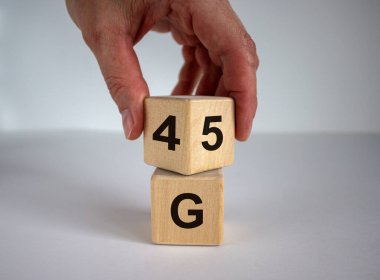Erkek eli, 4 ve 5 numaralarla küpü çevirir. 4 ya da 5 G teknoloji konsepti. Güzel beyaz arkaplan, kopyalama alanı.