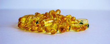 Sarı vitamin hapları, balık yağı, mavi arka planda Omega E vitamini hapları. Web afişi. Güzel arkaplan.