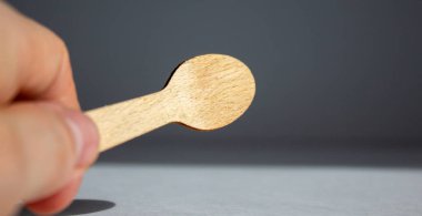 Beyaz arka planda tahta bir kaşık tutuyor. Güzel sıcak güneş ışığı.