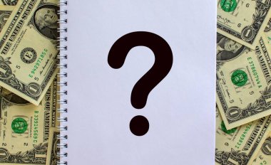 Dolar banknotlarının arka planında soru işareti olan beyaz bir not. Kavram. Boşluğu kopyala.