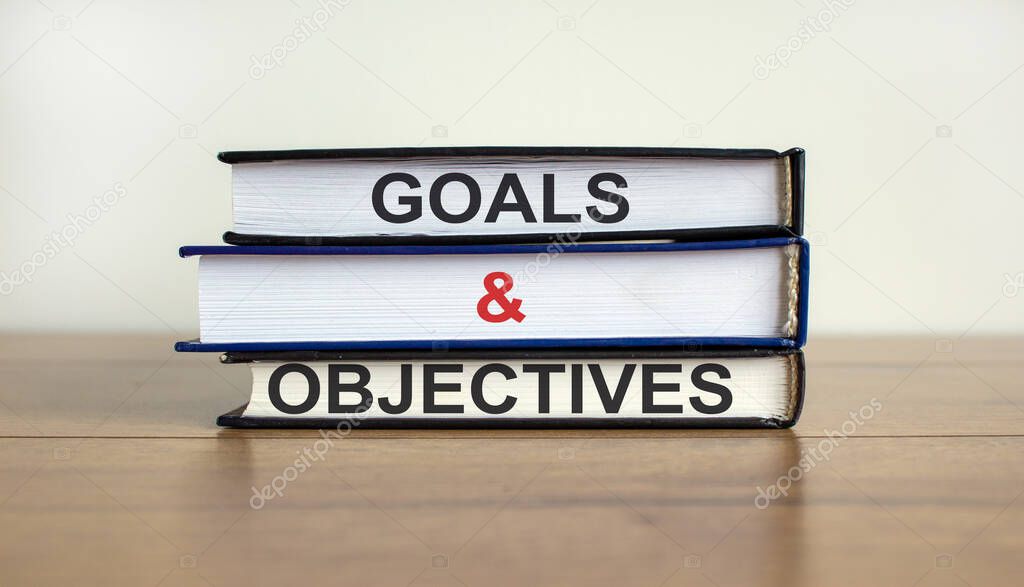 Books with text 'goals and objectives' on beautiful wooden table. White background. Business concept. Copy space.