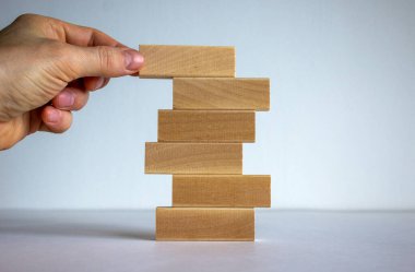 Başarı temeli konsepti. Erkekler ahşap kütüklerin üzerine ahşap bloklar koyarlar. Güzel beyaz arkaplan, kopyalama alanı.