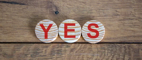 Wood circles with word 'yes' on beautiful wooden background, copy space. Business concept.