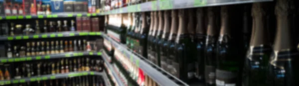 Beautiful blurred abstract background of shelf in supermarket. Alcohol showcase blurred background.