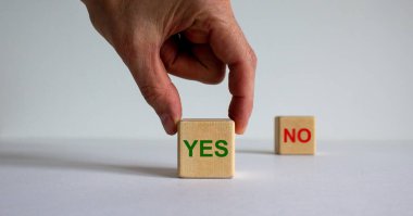 El, güzel beyaz arka planda 'evet' ve 'hayır' kelimelerini içeren iki küp arasında seçim yapıyor. İş konsepti.