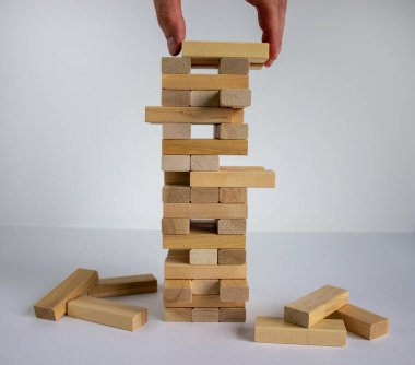 Mimari modelli ahşap blok kulesi. Yönetim ve strateji planı, büyüme işi başarı süreci ve takım çalışması riskini hesaba katın. Erkek eli. Güzel beyaz arkaplan, kopyalama alanı.