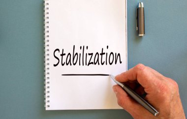 Erkek el yazısı 'stabilizasyon' beyaz notada, mavi arka planda izole. İş konsepti.