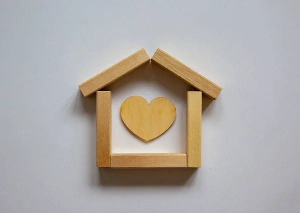 Wooden model of house from blocks. Heart sign. Place for your text. White background. Business concept.