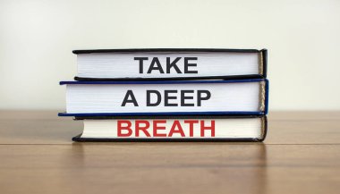 Güzel ahşap masada 'derin bir nefes al' yazılı kitaplar. Beyaz arka plan. İş konsepti.