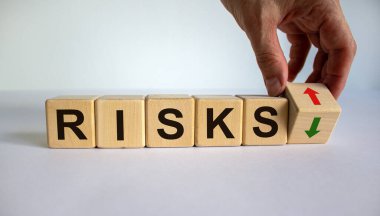 El bir küpü döndürüyor ve bir okun yönünü değiştiriyor. Bu da risklerin azaldığını ya da tam tersi olduğunu simgeliyor. Güzel beyaz arka plan, kopyalama alanı. İş konsepti.