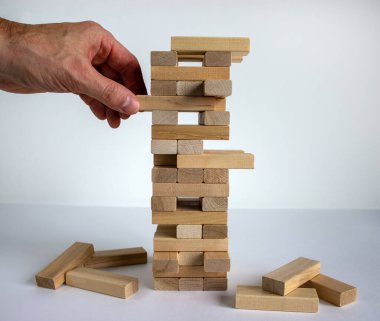 Mimari modelli ahşap blok kulesi. Yönetim ve strateji planı, büyüme işi başarı süreci ve takım çalışması riskini hesaba katın. Erkek eli. Güzel beyaz arkaplan, kopyalama alanı.