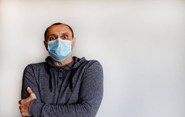 Korkunun ifadesi. Beyaz arka planda izole edilmiş koruyucu ilaç maskesi takan genç bir adam..