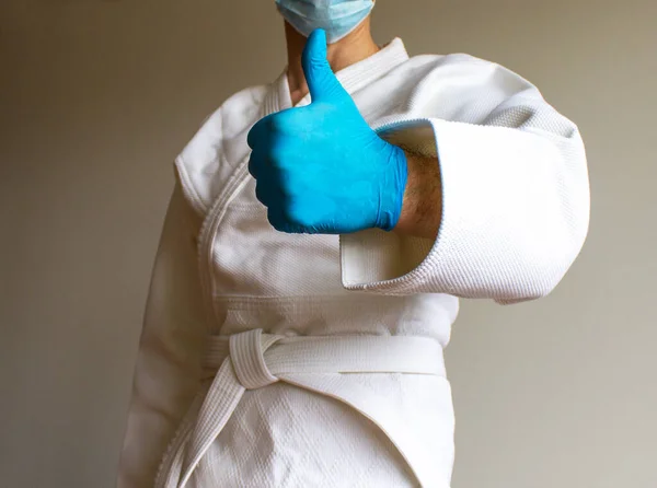 Covid 19パンデミックコロナウイルスのコンセプト 青い医療用手袋と医療用マスクを持つサンボ 柔術や他の武道のための白い着物の若い強い男 Okサイン — ストック写真