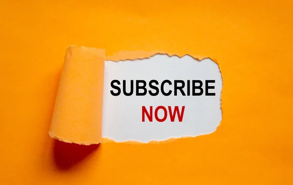 The words \'subscribe now\' appearing behind torn orange paper. Business concept. Copy space.