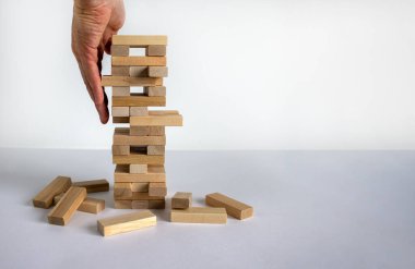 Mimari modelli ahşap blok kulesi. Yönetim ve strateji planı, büyüme işi başarı süreci ve takım çalışması riskini hesaba katın. Erkek eli. Güzel beyaz arkaplan, kopyalama alanı.