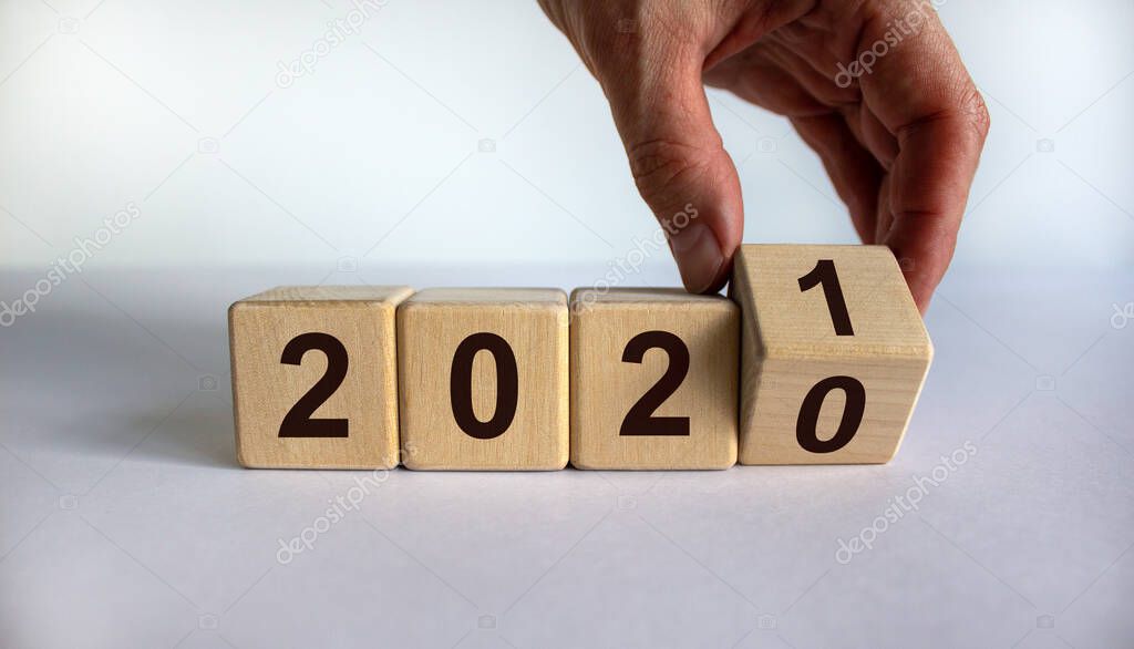 Hand turns a cube and changes the year '2020' to '2021'. Beautiful white background. Copy space.